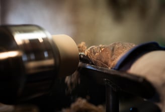 Gros plan sur un tour à bois en action, faisant jaillir des copeaux de bois qui s'accumulent en un p