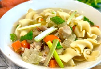 Chicken noodle soup in a white bowl.
