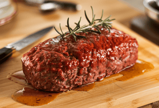 a juicy meatloaf on a cutting board with a knife