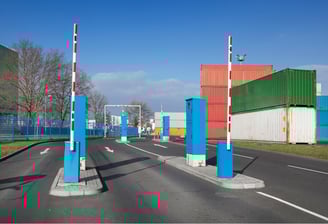 Automated gate system at sea port with barriers and container yard in background.