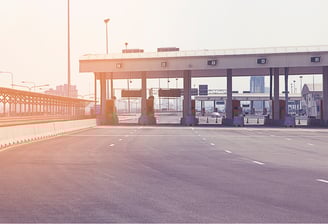 Empty highway toll plaza with sunlight representing an automated toll collection system.
