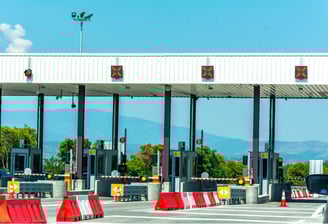 Toll booth with barrier, surveillance camera, and traffic lanes under smart toll control system.