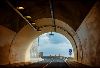 Inside view of a modern road tunnel with lighting and exit signage for smart monitoring and evacuation control.