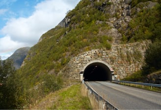 Stone-structured tunnel entrance on a mountain road for rural tunnel traffic and safety monitoring solutions.