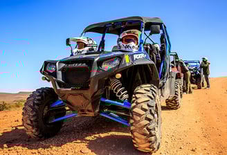 a group of people riding a quad bike buggy on a dirt road in the desert