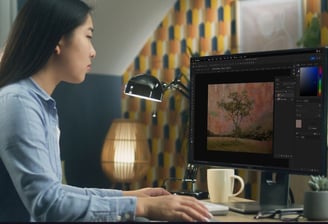 An artist using Photoshop to edit a digital artwork of a tree, focusing on creative effects