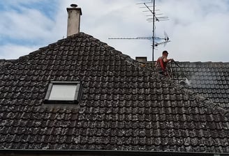 Couvreur réalisant un nettoyage en profondeur d’une toiture envahie par les mousses à Montbéliard, pour restaurer l’étanchéit