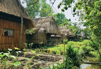 Traditional thatched-roof cottages surrounded by lush gardens at Saigon Garden Homestay.