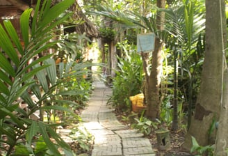 Traditional thatched-roof cottages surrounded by lush gardens at Saigon Garden Homestay.