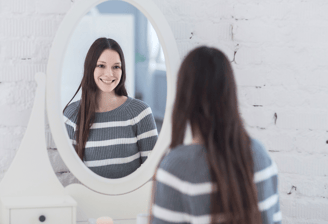 Mujer joven contemplándose al espejo. Se nota contenta consigo misma, buena autoestima.