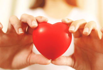 Dos manos en primer plano sosteniendo con cuidado un corazón de juguete. Da a entender que se cuida