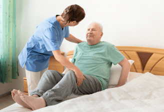 physiotherapy at home for seniors - a physio is helping an elderly man into bed in his home
