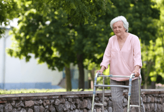 a woman with a walker frame walking outside - The London Physio