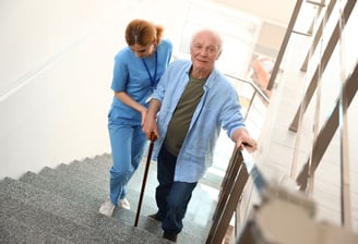 An elderly patient practising walking up stairs with The London Physio