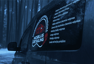 automobilis stovintis tarp medžiu, su ant šono priklijuotais lipdukais