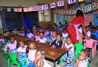 a woman standing in front of a classroom with a group of children