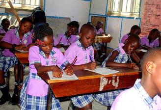 a group of children in school uniforms sitting at desks