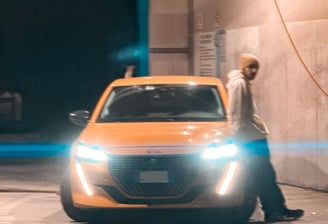 Ragazzo accanto a Peugeot 208 accesa. Passione per le auto raccontata in un blog autentico