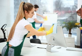 a woman cleaning a computer screen in a room