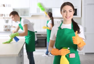 a woman in green aprons holding a cleaning sponge