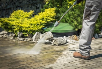 A man using a powerful pressure washer to clean a sidewalk