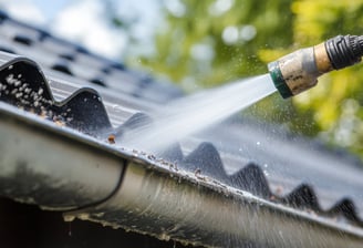 A gutter being cleaned with a pressure washer