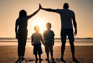 uma família de três pessoas em pé na praia