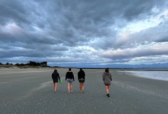 four women walking on a beach