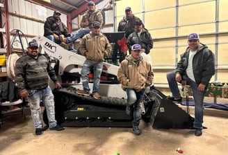 a group of men standing around a skid stear