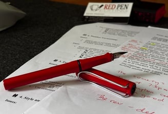 Red Lamy "Safari" fountain pen resting on manuscript that has been annotated by Red Pen Editing