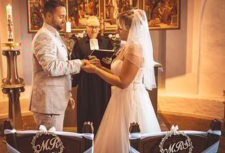 Braut und Bräutigam bei der Trauung in einer Kirche, umgeben von festlicher Dekoration.