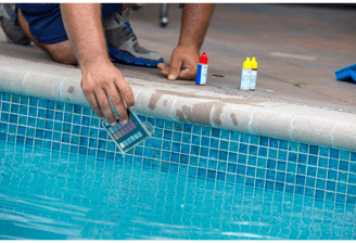 Image of a pool tech kneeling poolside performing a water test