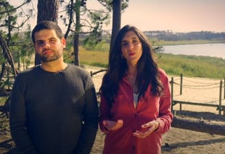 a man and woman standing in front of a lake
