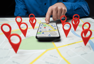 Hand using map on smartphone with location pins | Local SEO and business targeting