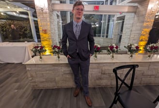a man dressed in grey suit, brown shoes, and blue dress shirt & tie