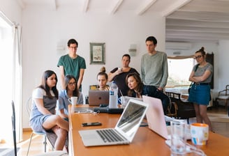 A team gathered around a laptop on a table, attending a virtual meeting.