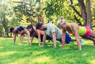 a group of people doing push ups in a park