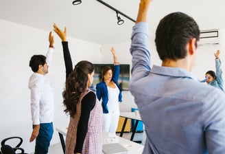 a group of people standing in a room with their hands up