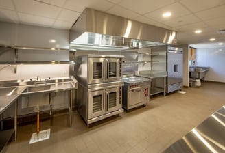 commercial kitchen setting containing commercial ovens and various commercial appliances