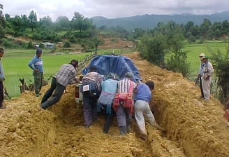 A team pushing a vehicle along a muddy track