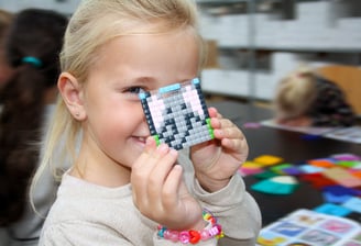 Happy girl showing the picture of an elephant made of colorful silicone pixel squares