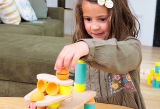 The girl is creating a unique construction from colorful silicone and wooden figures