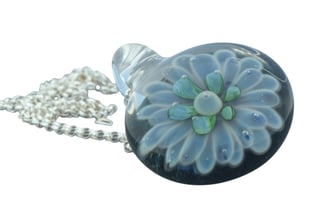 a glass pendant necklace with a flower on it