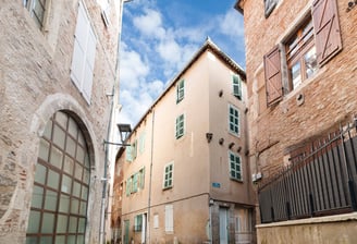 Vue grand angle de trois bâtiments anciens dans les ruelles étroites de Cahors, ciel bleu