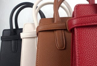 a row of four different colored handbags