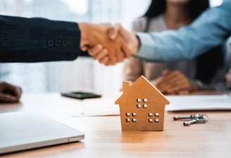 A handshake between two professionals over a signed real estate contract, symbolizing success