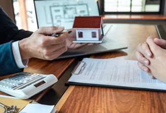 A Realtor sitting at a desk with a Seller explaining his expert services