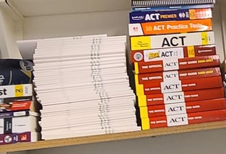 Test prep books on a shelf displaying some of the tests Benny specializes in