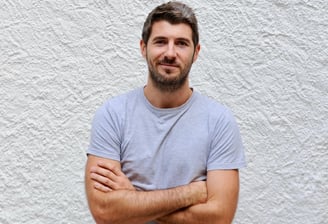 un homme avec une barbe, debout devant un mur blanc