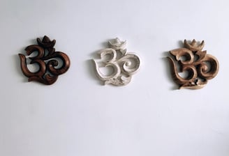 three wooden carvings of a Om religous symbol